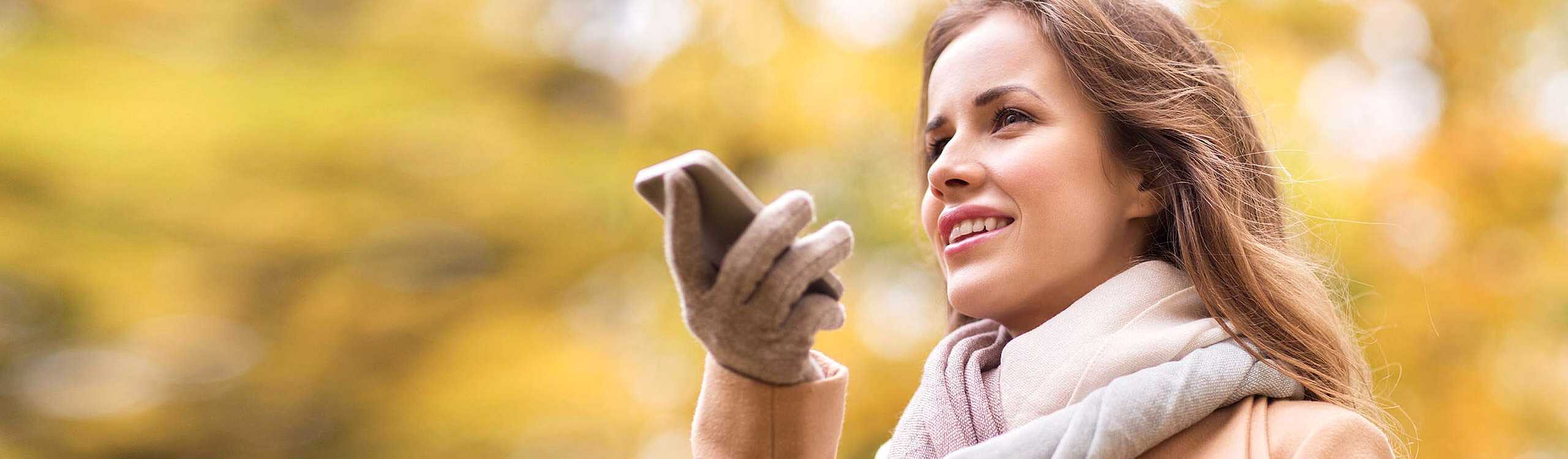 Junge Frau telefoniert über die Freisprecheinrichtung ihres Smartphones