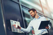 Portrait of a young happy businessman who rings the bell at a door intercom