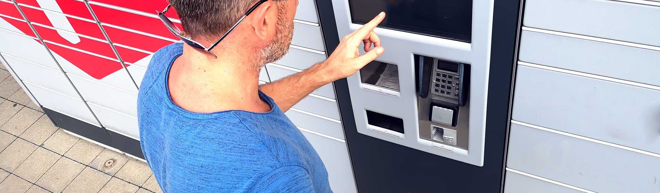 Ein Mann gibt ein Paket an einer Packstation auf.